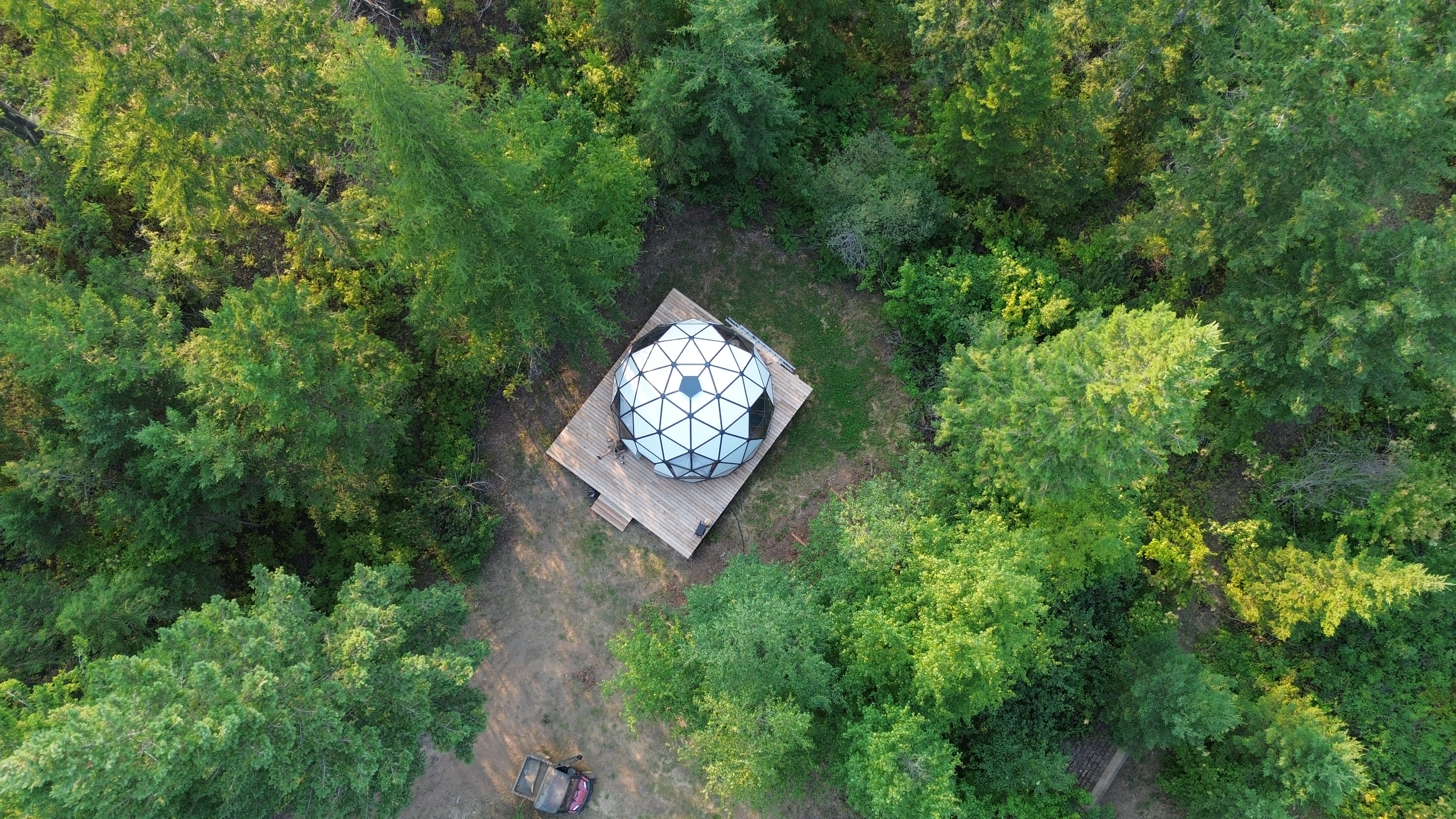 Aerial view of the geodesic dome surrounded by forest